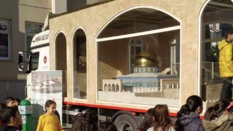 أطفال يتجمّعون أمام المجسّم المعروض خلف زجاج